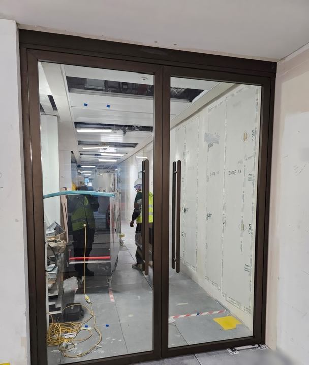 A completed glazed bronze-framed fire door set to an office corridor.