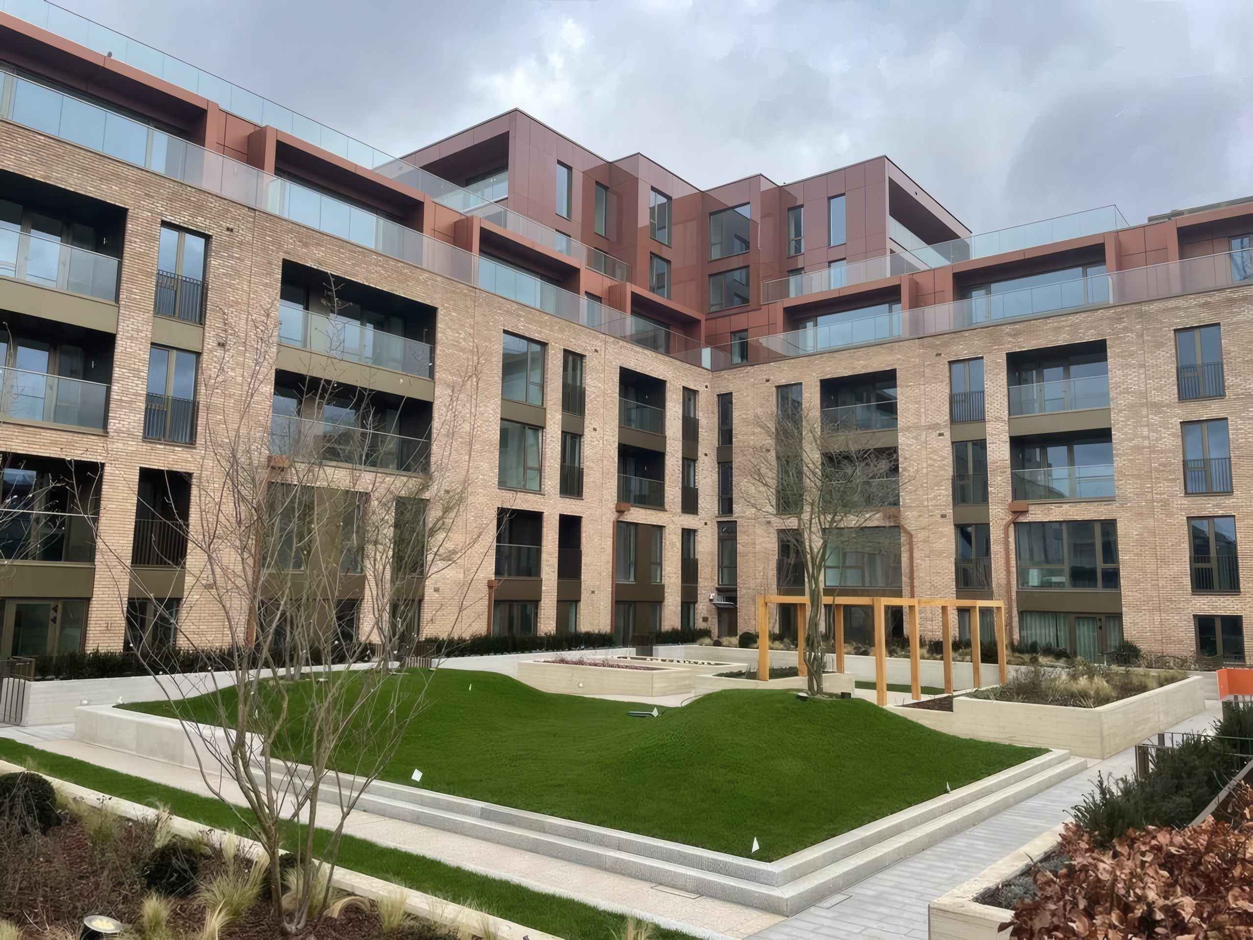 Terracotta-finish cladding and glazed balustrades around a landscaped residential courtyard in London.